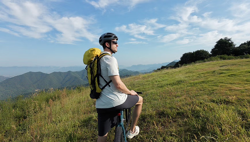 Dron DJI Neo 2 śledzi rowerzystę w terenie górskim.