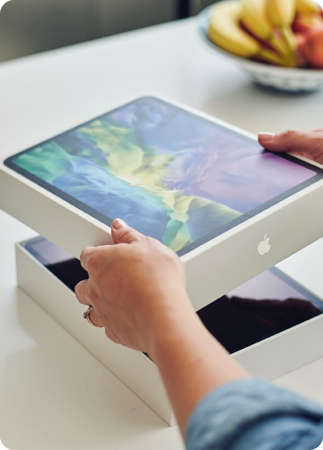 Osoba otwierająca pudełko z nowym iPadem zakupionym w programie pracowniczym