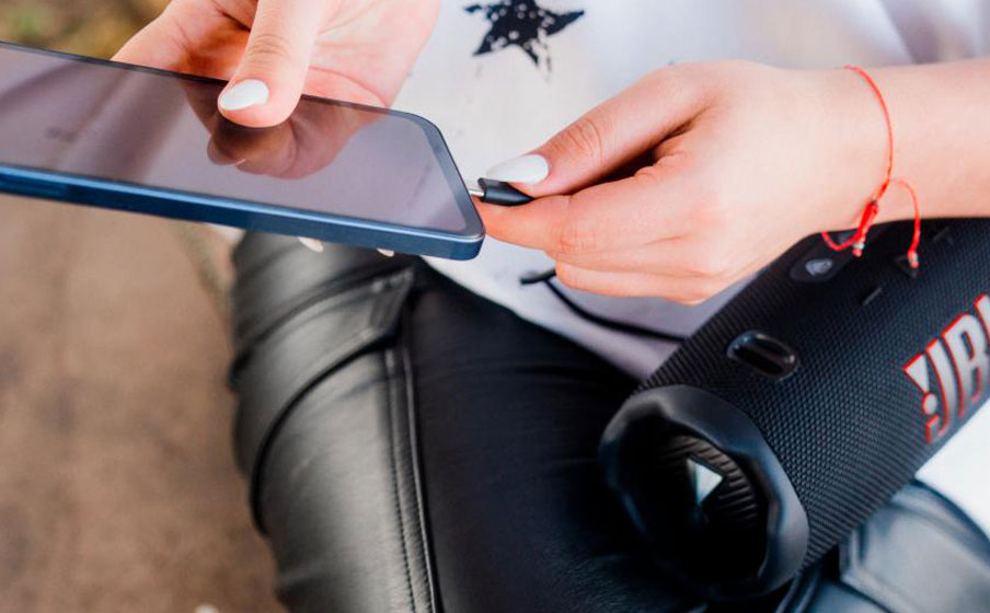 Osoba podłącza smartfona do JBL Charge 6, aby wykorzystać go jako powerbank i naładować telefon.