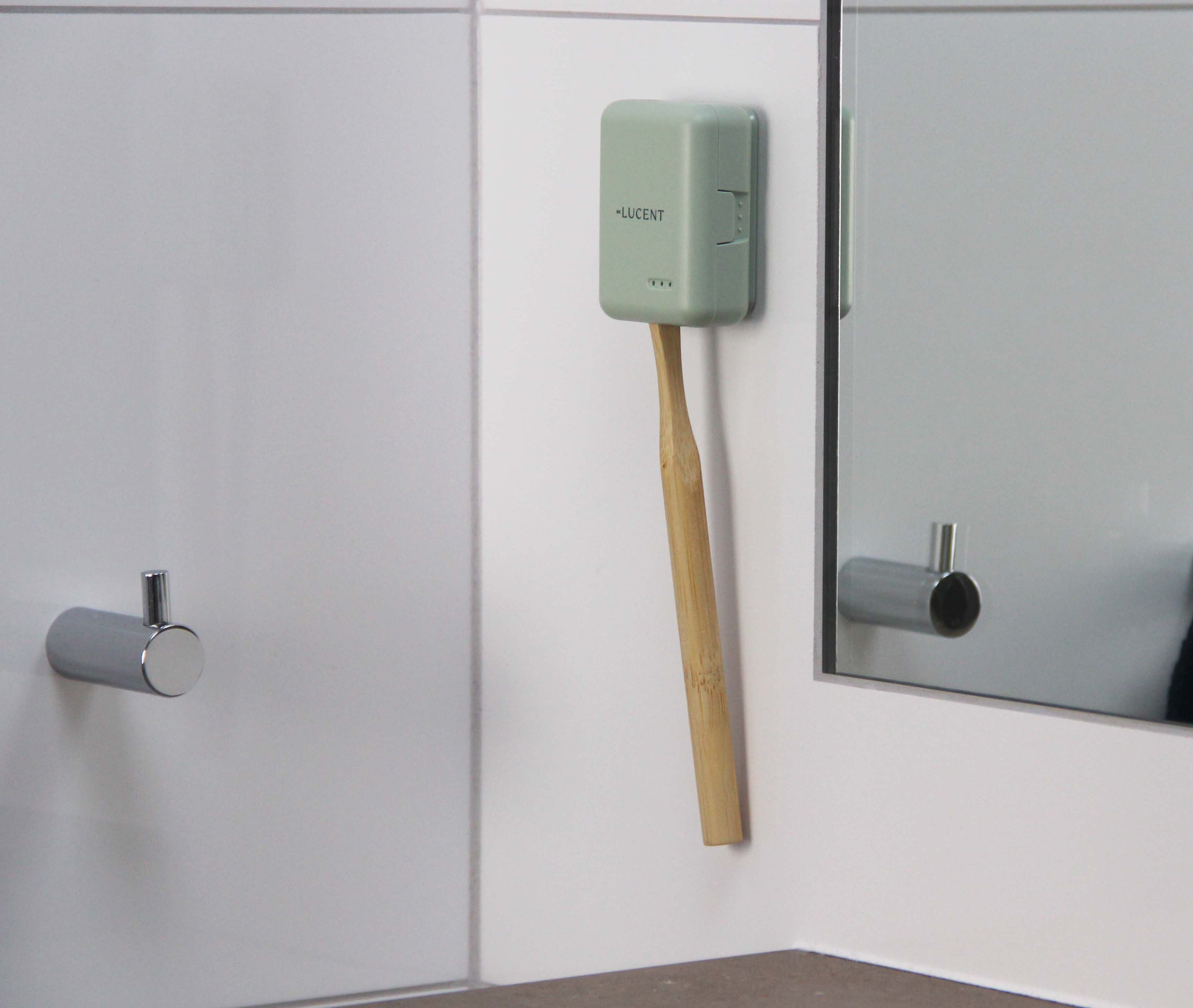 Sterylizator Lucent Aurora Toothbrush Steriliser ze szczoteczką do zębów zamontowany na ścianie w łazience obok lustra