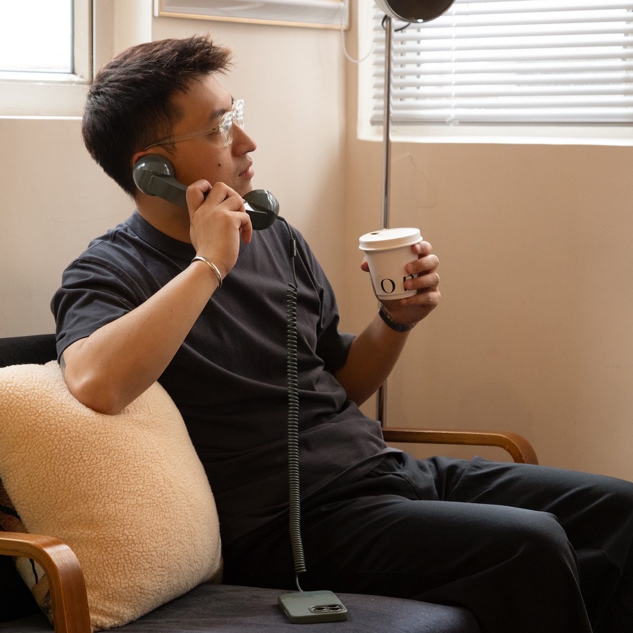 Użytkownik rozmawia przez słuchawkę Native Union POP Phone pijąc poranną kawę