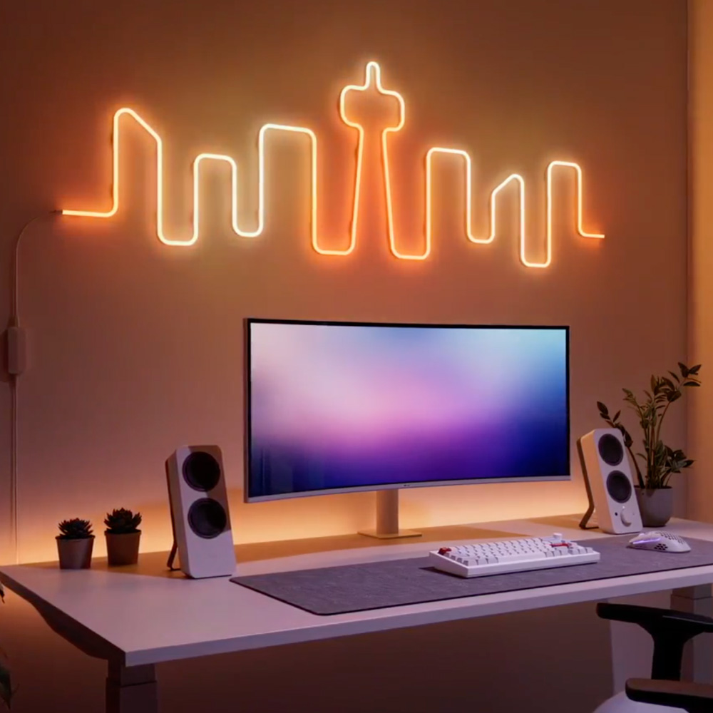 Listwa Nanoleaf Smart Multicolour Rope Light oświetla ścianę nad monitorem.