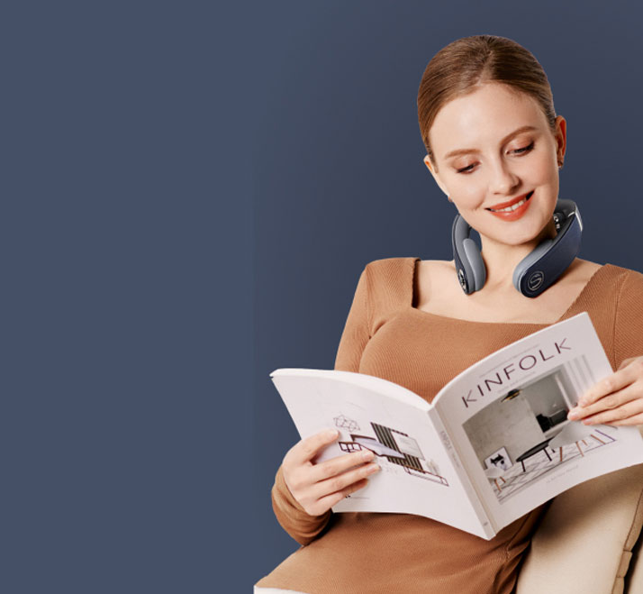 Osoba używa masażera SKG W7 Pro-Fold siedząc wygodnie na fotelu i przeglądając katalog