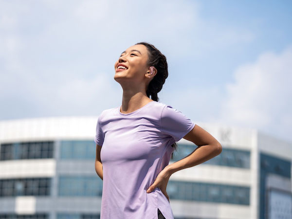 Kobieta używa słuchawek Shokz OpenFit Air podczas aktywności na świeżym powietrzu