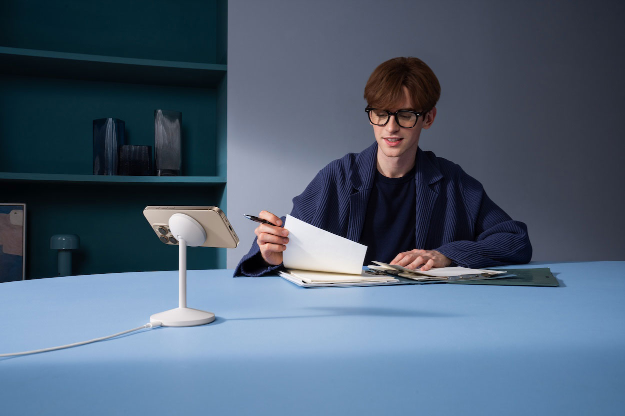 Użytkownik iPhone'a ładuje telefon na ładowarce Anker MagGo Wireless Charger podczas przeglądania dokumentów.