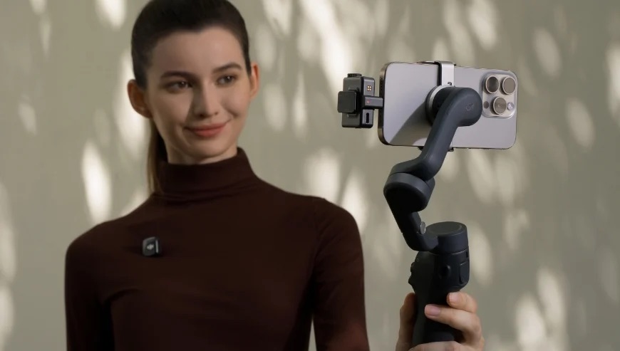 Osoba trzyma gimbala, na którym znajduje się smartfon z zamontowanym mikrofonem DJI Mic Mini.