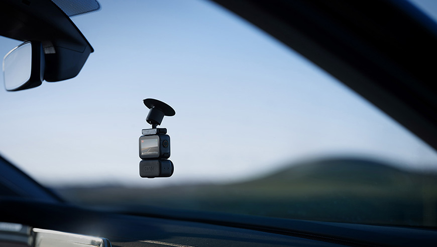 Zdjęcie przedstawia kamerę zamocowaną do szyby przedniej samochodu