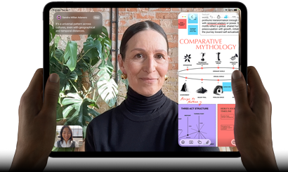 Widoczny od przodu ustawiony poziomo iPad Pro w kolorze gwiezdnej czerni, zaokrąglone rogi, czarna ramka wyświetlacza. Ręce trzymają urządzenie z lewej i prawej strony, na ekranie tłumaczona na żywo rozmowa przez FaceTime. Widać też aplikację edukacyjną z prezentacją „Comparative Mythology”, z tekstem, diagramami i odręcznymi notatkami