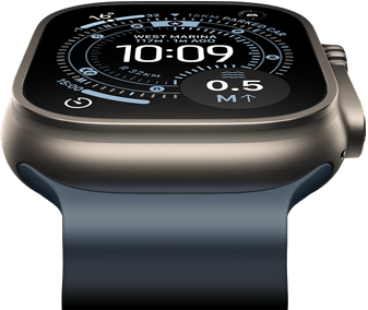 Pochylony do przodu Apple Watch Ultra 3 z kopertą z tytanu w kolorze naturalnym, widać kompas na tarczy Orienteering, zegarek ma pasek Ocean w kolorze marynarskiego granatu