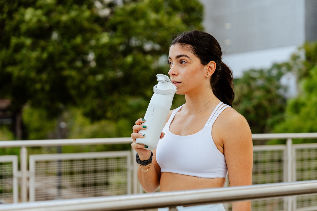 Użytkownik używa butelki LARQ Bottle PureVis™ 2 podczas treniongu w plenerze
