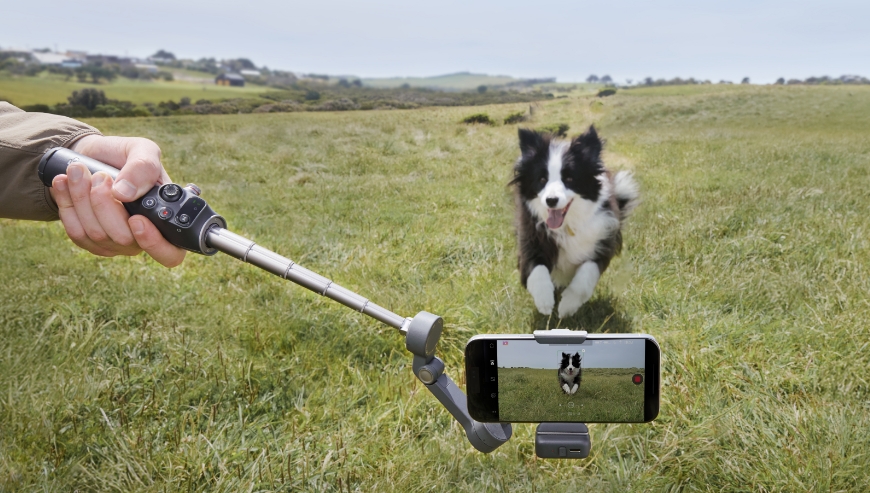 Ilustracja przedstawia gimbal DJI Osmo Mobile 7P z wysuniętym wysięgnikiem ułatwiającym dynamiczne nagrania w ruchu.