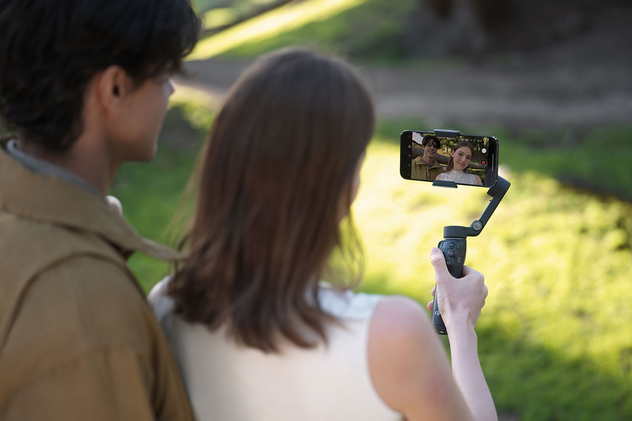 Osoba nagrywająca wideo korzysta z wysięgnika gimbala DJI Osmo Mobile 8.