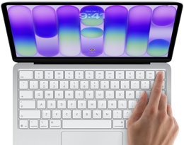 MacBook Neo w kolorze srebrnym z widocznym ekranem logowania i palcem osoby używającej czytnika Touch ID w prawym górnym rogu klawiatury