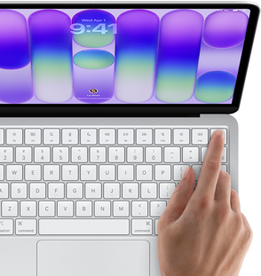 MacBook Neo w kolorze srebrnym z widocznym ekranem logowania i palcem osoby używającej czytnika Touch ID w prawym górnym rogu klawiatury